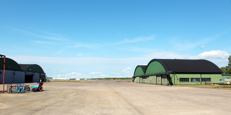 Gröna hangarer sedda utifrån en solig dag på en flygplats. 