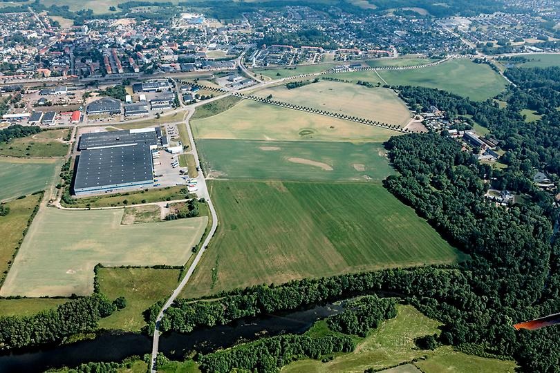Flygbild över området Bruksallén. Stora gröna ytor omges av skog och bostadsområden.