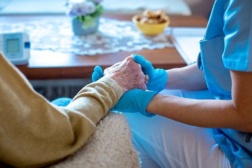 Sjuksköterska håller en seniors hand.