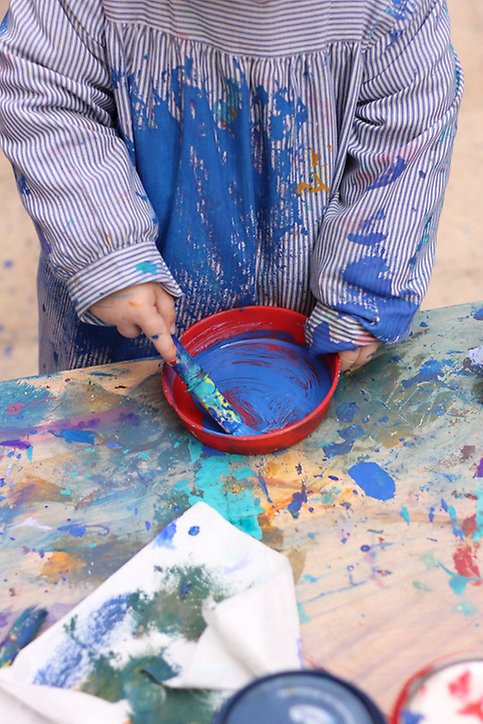Foto på ett litet barn som målar och spiller en färg omkring sig
