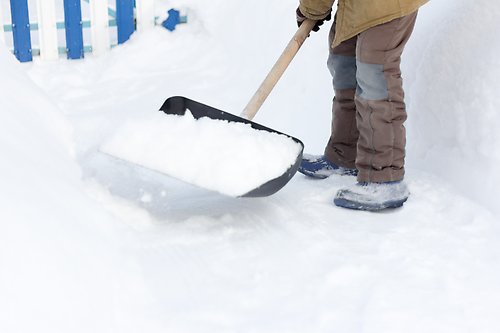 En person skottar snö med en stor skyffel