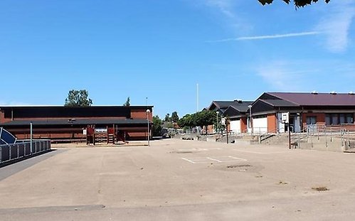 Antilopenskolans skolgård. En stor och öppen plan för lek. Till höger finns skolbyggnaden, till vänster gymnastiksalen.